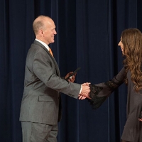 Doctor Potteiger shaking hands with an award recipeint in a long sleeved grey dress